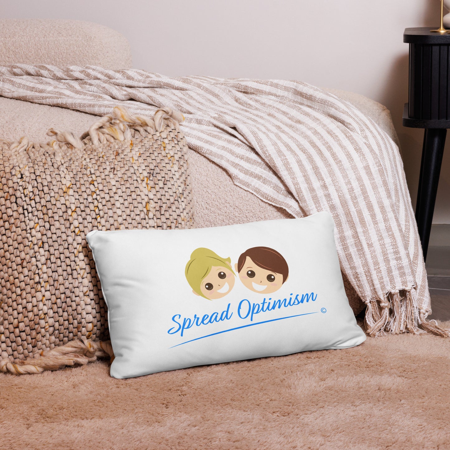 Unique 20x12 pillow, encouraging everyone to 'Spread Optimism,' enhancing the appeal of a pink carpet and a lovely pink checkered scarf.