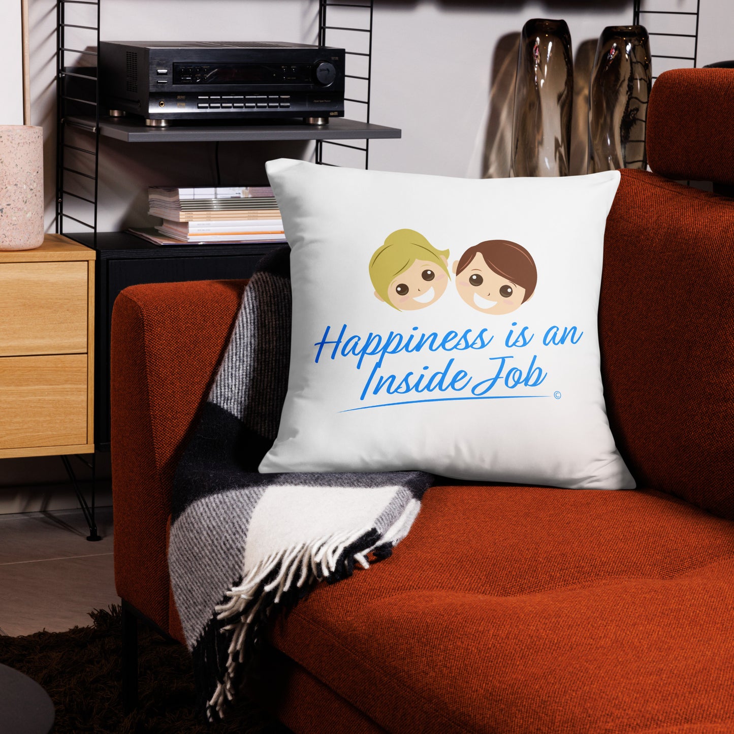 Empowering 22x22 throw pillow featuring the uplifting message 'Happiness is an Inside Job,' making a statement on a red couch and a trendy checkered scarf.