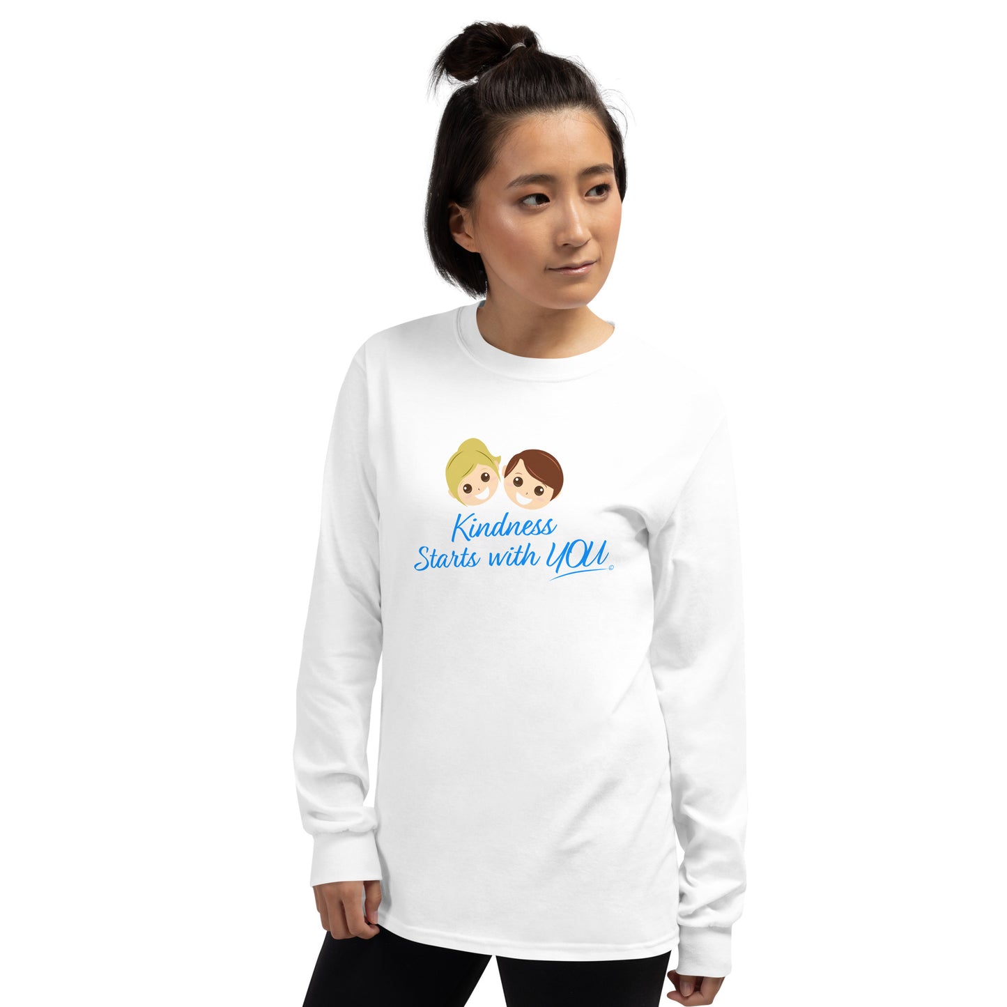 A confident young woman proudly wearing a long sleeve shirt in white, featuring the inspiring quote 'Kindness Starts with You' in bold lettering.