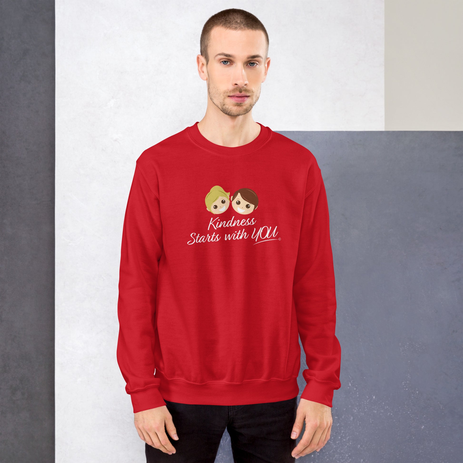 A confident man modeling a cozy unisex sweatshirt in red, featuring the uplifting quote 'Kindness Starts with You' in bold lettering.