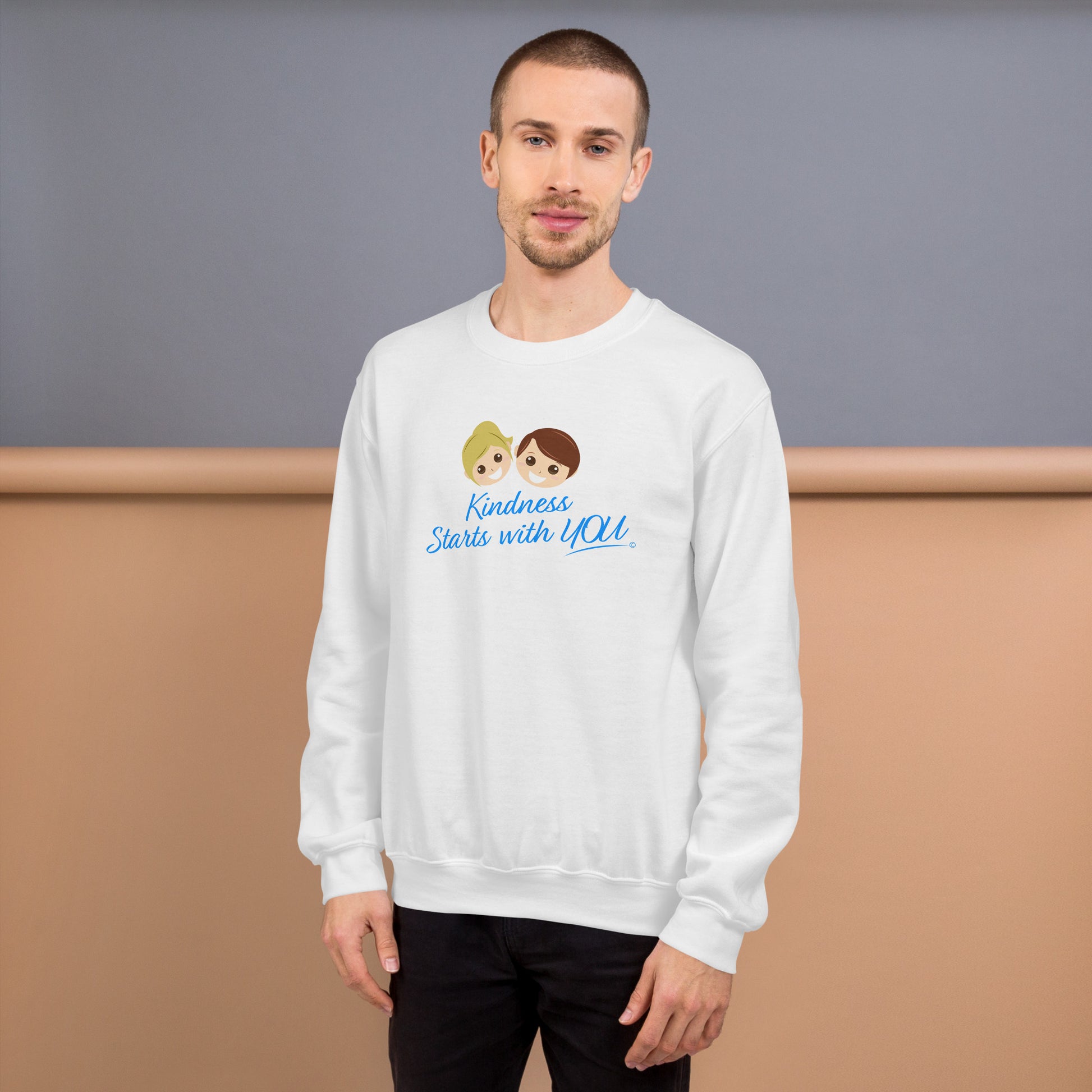 A confident man modeling a cozy unisex sweatshirt in white, featuring the uplifting quote 'Kindness Starts with You' in bold lettering.